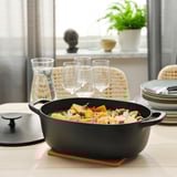 Cast iron casserole with veggies and wine on wooden table.