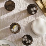 Four glasses with ice, one with lemon. On beige cloth, with jug and napkin. Practical for chilled drinks.