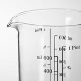 Clear glass measuring jug with black volume markings, spout for pouring.