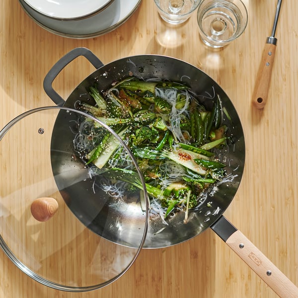 Stir-fried vegetables and noodles in wok on table.