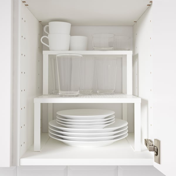 White shelf with stacked plates, glasses, and mugs for extra storage.