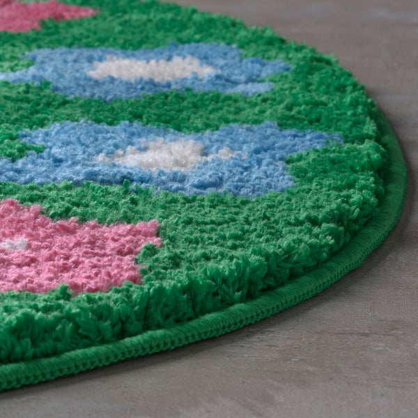 Round, plush bath mat with green border, blue and red floral pattern, soft texture, high quality.