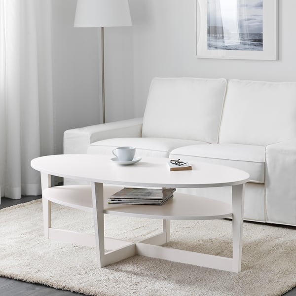 Modern living room with scandinavian-style coffee table. Coffee cup, remote, and magazines on shelves, near white sofa on light rug.