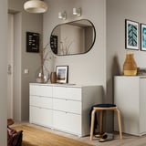 Organized entryway with white storage units, mirror, and decorative items.
