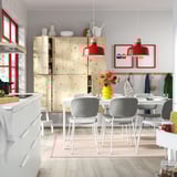 Modern dining room with light wooden extendable table, gray chairs, red pendant lamps, and yellow vase.