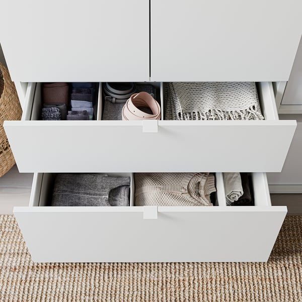 Neatly organized drawer units with clothes; light wood, rectangular, minimalist design.