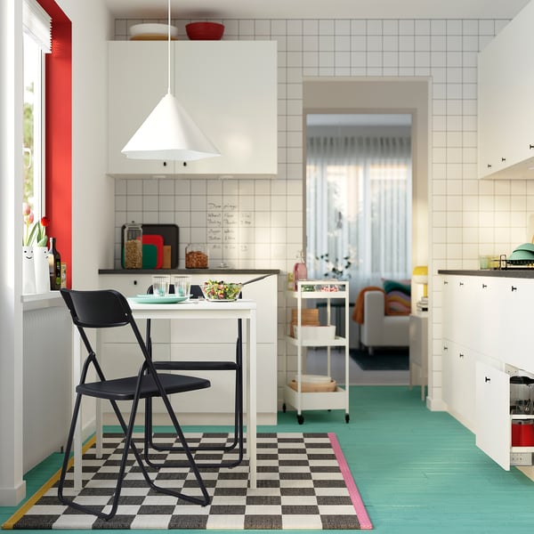 Small black VIHALS folding chair near a white counter in a colourful kitchen.