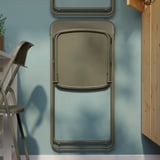 Foldable dining table mounted on blue wall, demonstrating space-saving design. Steel framed with adjustable shelf below for storage.