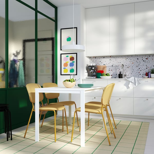 Modern kitchen with white table, four yellow chairs, foam-padded seats, and green-framed glass wall.