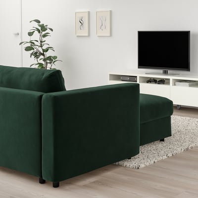 Modern living room with emerald green VIMLE sectional sofa, wood floor, white tv stand, plant, and artwork.