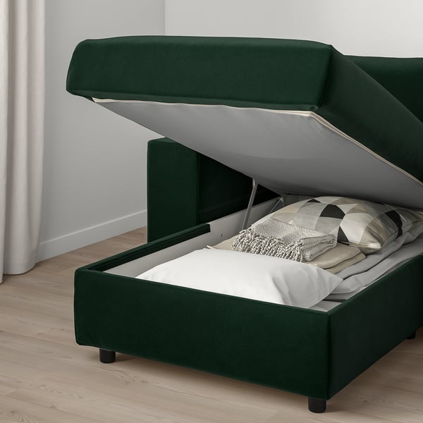 Dark green sofa bed with storage ottoman, open to show bed and linens.