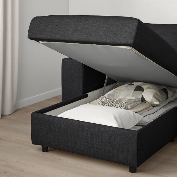 Image shows a dark grey VIMLE sofa with open storage under seat, revealing bedding and pillows inside.
