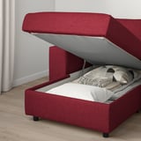 Red sofa with storage ottoman, open lid revealing folded blankets.