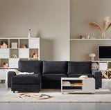 Modern living room: dark gray l-shaped VIMLE sectional sofa on beige rug, facing white storage units with colorful accents and tv.