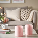 Pink candle holders on table with coffee mug, books and couch.