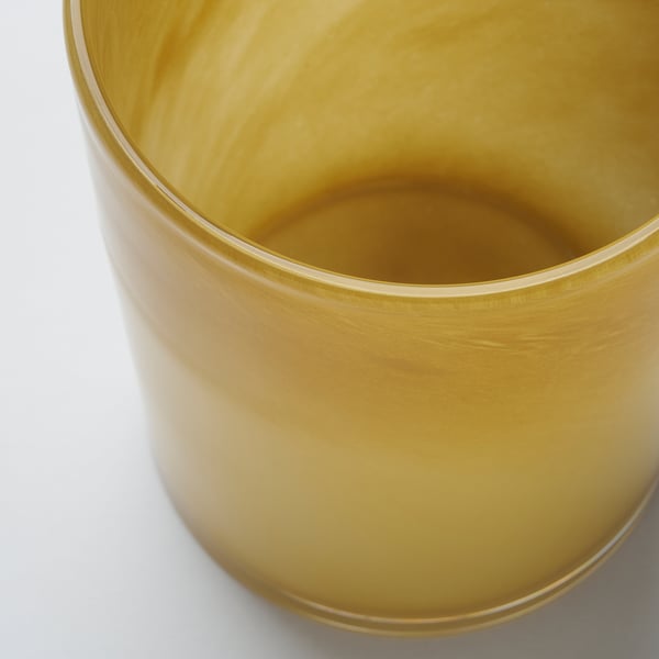 Golden glass candle holder, smoothly polished, reflecting light. Mouth-blown craftsmanship evident in intricate surface details.