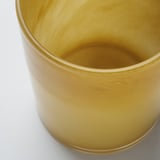 Golden glass candle holder, smoothly polished, reflecting light. Mouth-blown craftsmanship evident in intricate surface details.