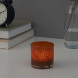 VINDSTILLA: orange glass candle holder with a decorative swirl pattern. Glows warmly when lit, adding ambiance to any room.