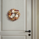 Wreath of dried plants and white flowers on gray door with black handle.