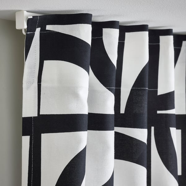 Black and white patterned curtains with tabs for hanging, providing privacy and style.