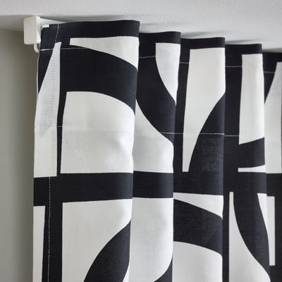 Black and white patterned curtains with tabs for hanging, providing privacy and style.