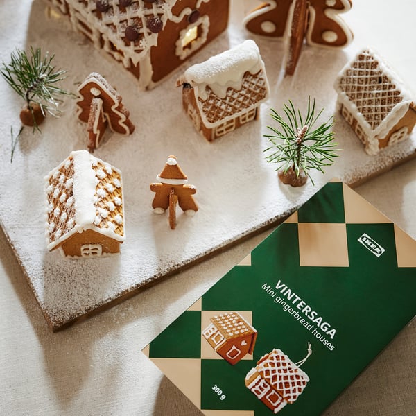 Gingerbread houses & person from IKEA VINTERSAGA, decorated with pine branches on snow, with a 300g packet.