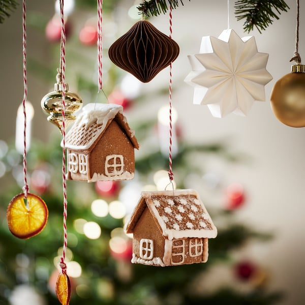 Miniature gingerbread houses hang from strings, along with various ornaments like a star and baubles, creating a festive christmas decoration scene.
