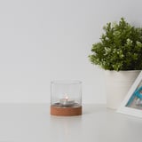 Tealight holder with cork base on table beside plant and frame.