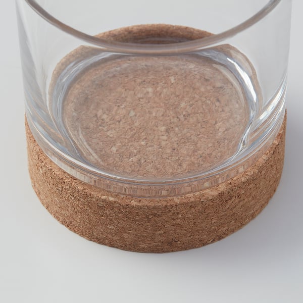 Clear glass candle holder with cork base, reflecting soft light.