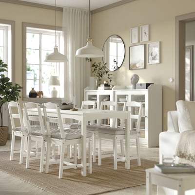 Modern dining area with white furniture and hanging lamps. Minimalist design.