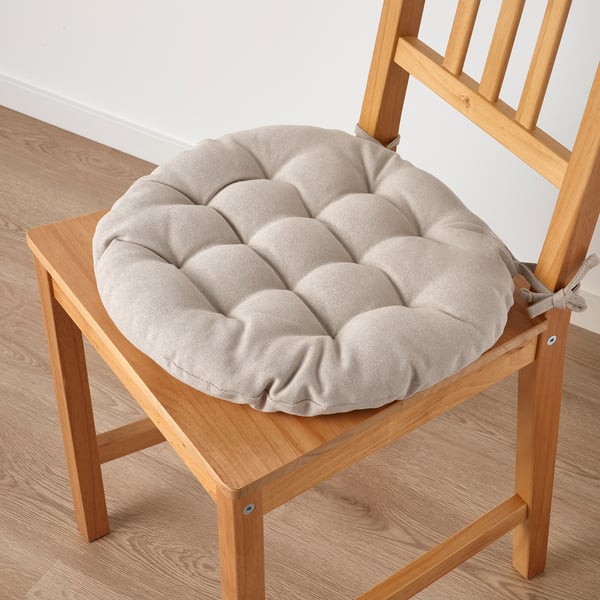 Chair with thick, round cushion. Beige color, tied for secure fit.