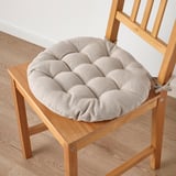 Chair with thick, round cushion. Beige color, tied for secure fit.