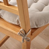 Light wood chair with thick, beige, cushioned seat pad tied on, offering comfort.
