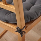 A grey chair cushion tied to a wooden chair for added comfort.