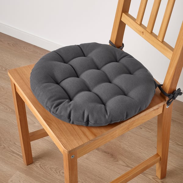 A chair with a dark grey padded seat cushion attached, providing comfort and style. The cushion is secured with fabric ties.