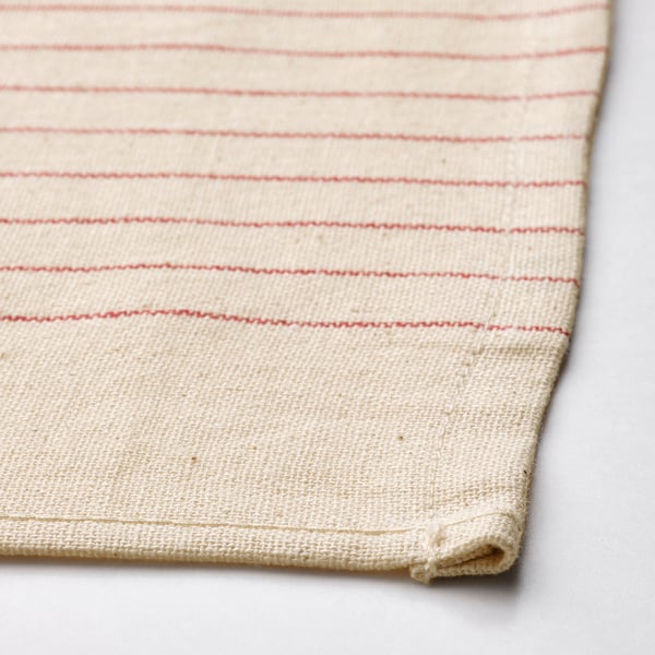 Folded beige cotton napkin with red stripes on gray surface.
