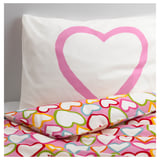 Heart-shaped pillow with vibrant, multicolored hearts on a pink background, showcasing soft, durable, cotton fabric.