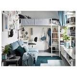 Small space bedroom with white loft bed, blue couch, grey rug, plants, and desk under bed.