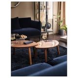 Modern living room with blue velvet couch, nesting coffee tables, wine glasses, and shaggy dark blue rug.