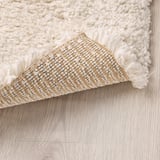 Fluffy white rug with textured yarn, shown with anti-slip mesh underlay.