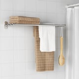 A bathroom featuring VOXNAN towel rail and shelf with four towels and a brush.