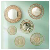 Wall multiple round wicker mirrors in natural tones. Designs vary, adding texture. Applied on green wall.