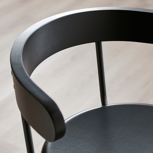Black bar stool with curved backrest and armrest, craftsmanship details visible.