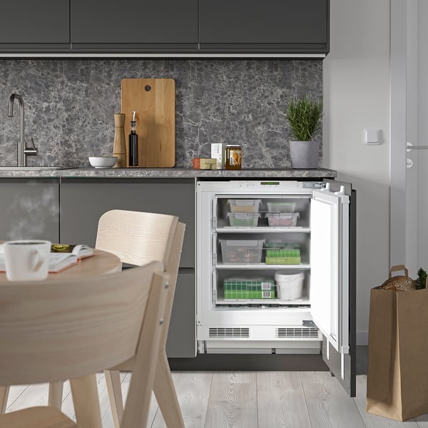 Small kitchen with integrated under-counter freezer, displaying three organized drawers.