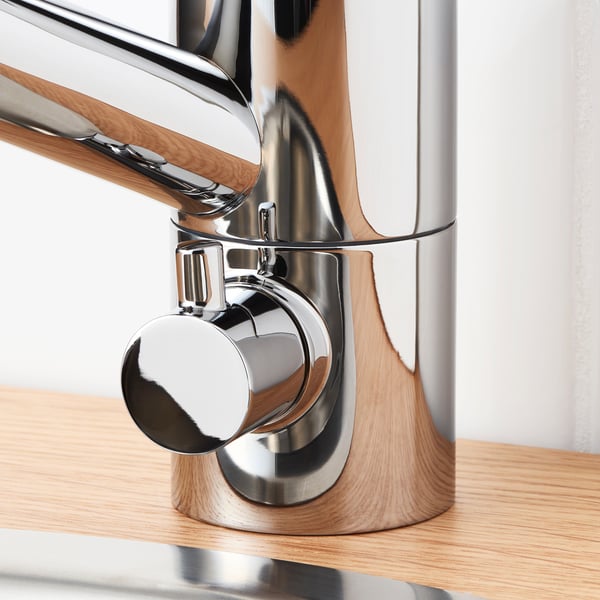 Modern chrome faucet mounted on wooden counter, showcasing sleek design and durable materials.