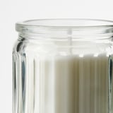 Ren, räfflad ljusburk i glas, klar med blekgult vax, välgjord och detaljerad.