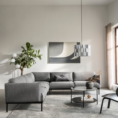 Modernt vardagsrum med grå ÄPPLARYD sektionssoffa, abstrakt konst, pendellampa, runt soffbord och stort fönster med beige gardiner.