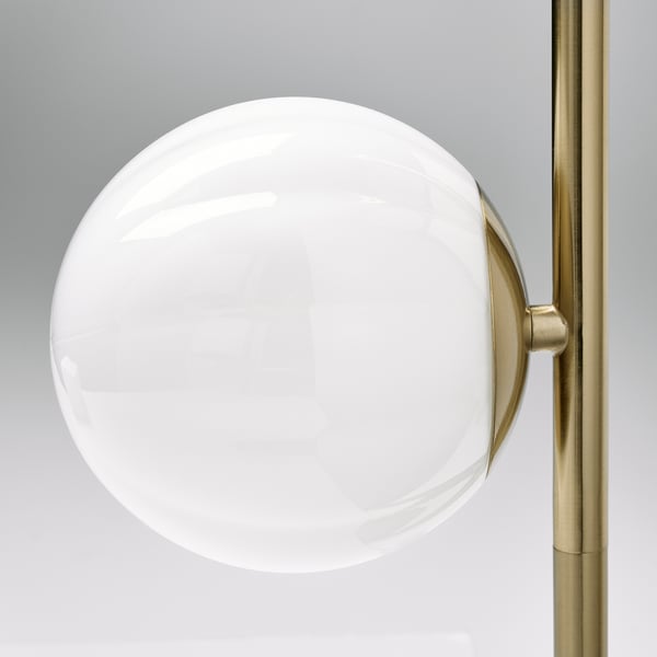 Slank modern lampa med en stor, rund, vit glasglobsskärm. Guldmetallbas, elegant design.