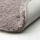 Närbild av mjuk, plysch, beige badrumsmatta med strukturerad yta och halkfri baksida.