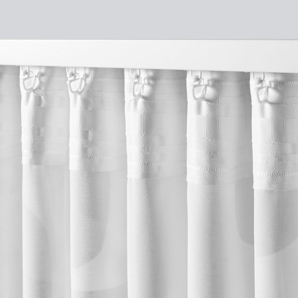 Vita gardiner med geometriska mönster mjukt draperade, vilket gör att ljus och luft kan passera igenom, vilket ger avskildhet. Kan hängas via flikar eller krokar.
